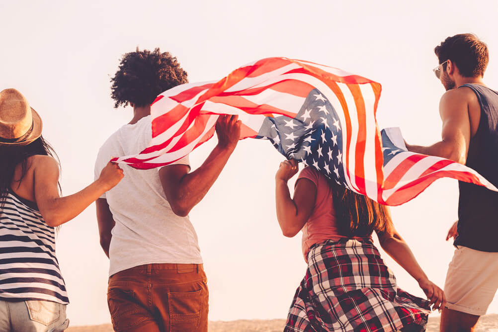 Las mejores loterías internacionales 4 personas caminan sosteniendo la bandera de Estados Unidos