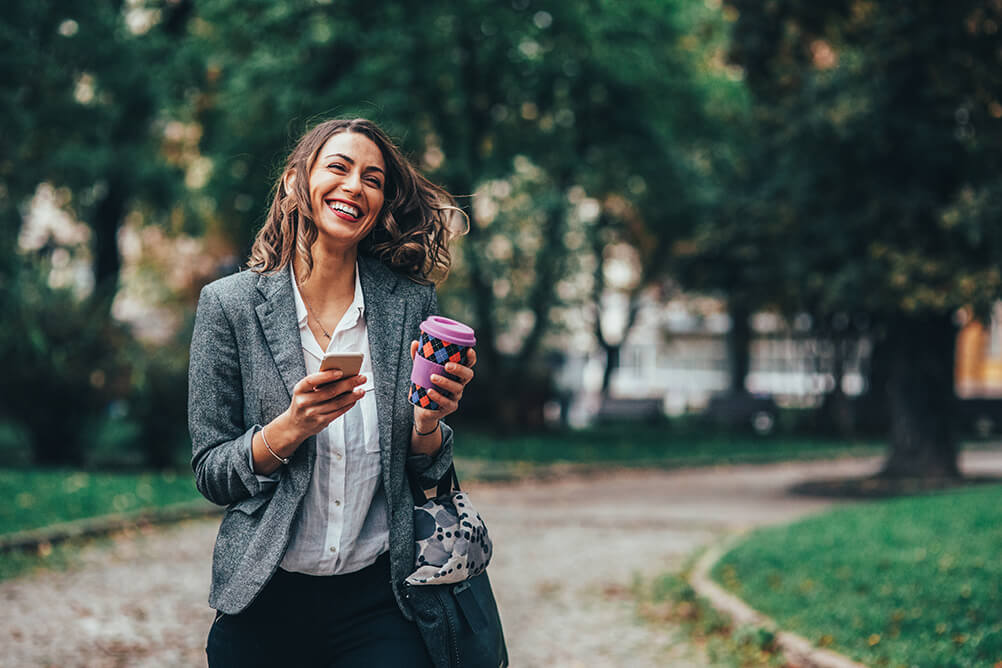 Mujer caminando en el parque con su celular