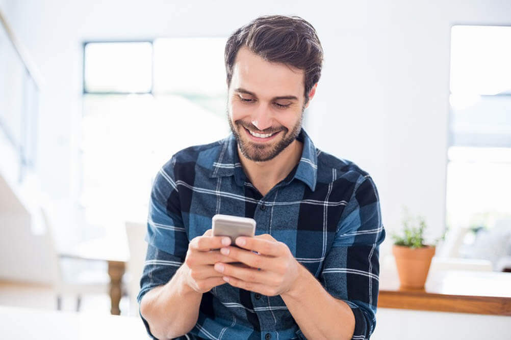 Hombre feliz revisando su teléfono celular
