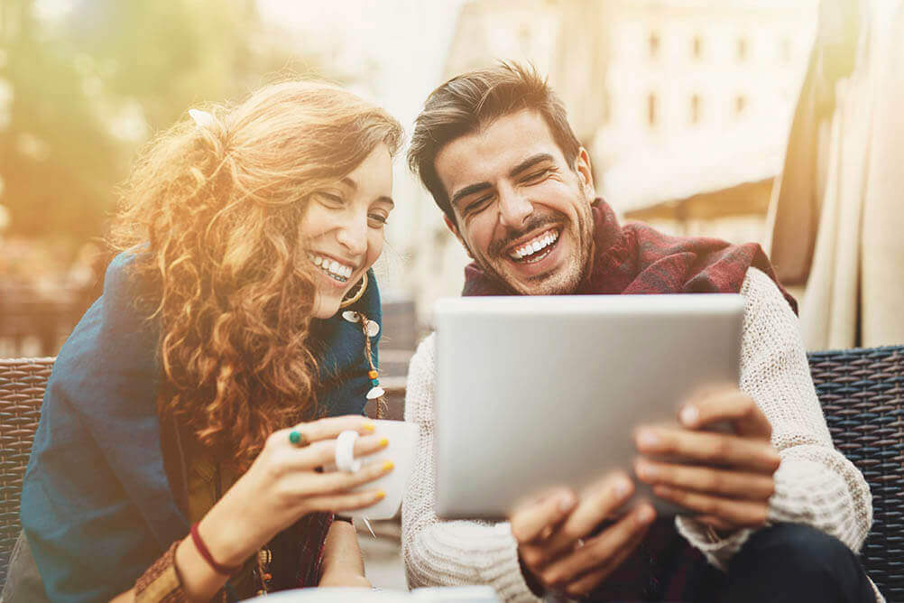 Pareja sonriendo mientras usan una tablet