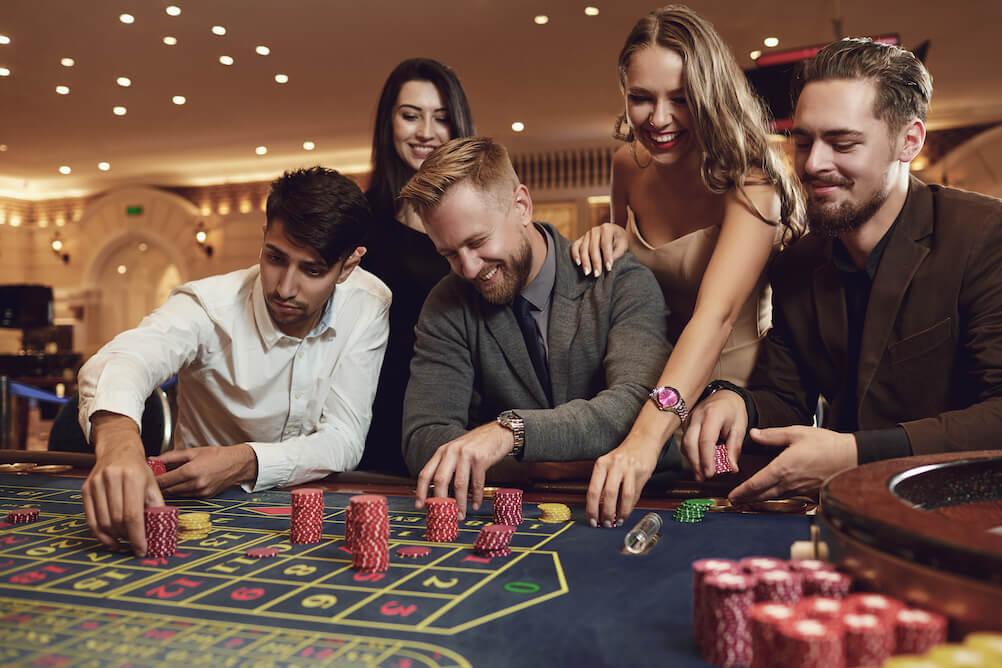 Tres hombres y dos mujeres están jugando a la ruleta. Revisaron las probabilidades de los juegos de casino antes de jugar.