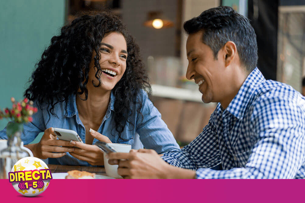 Una mujer y un hombre mirándose el uno al otro con sus móviles en la mano hablando sobre cómo apostar en la lotería Tris en línea con Lottoland.